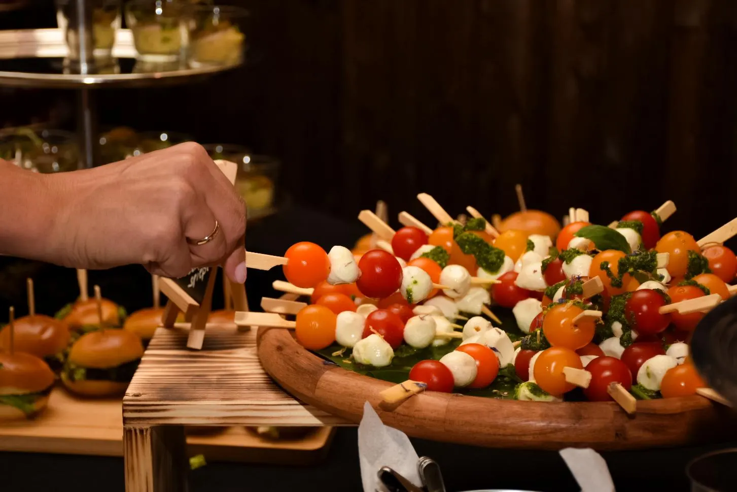 Hand nimmt einen Tomaten-Mozzarella-Spieß vom Buffet
