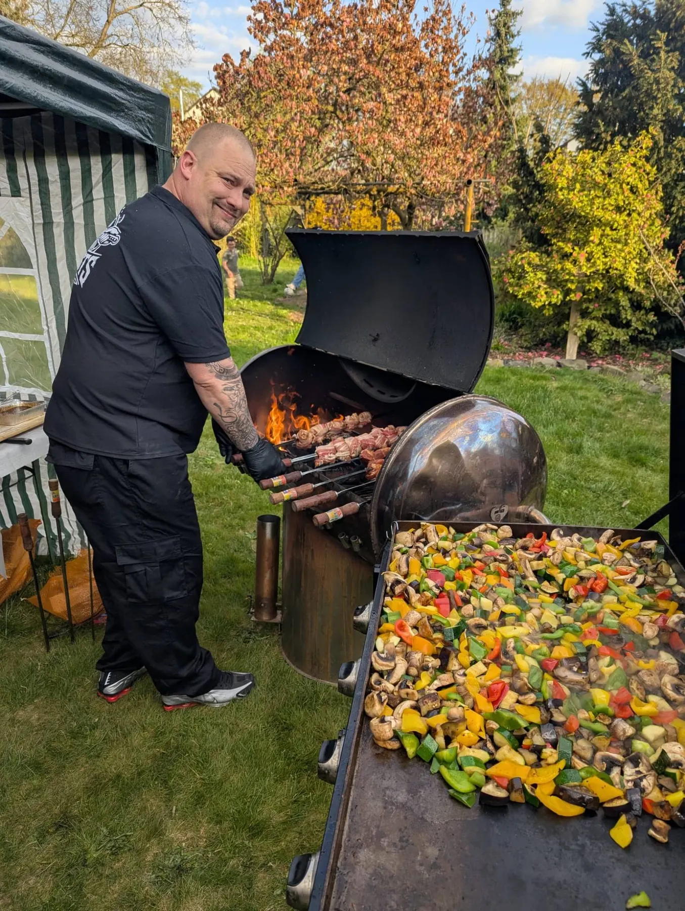 Koch am Fassgrill mit Fleischspießen und Gemüse auf der Plancha
